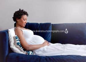 Mom to be laying on couch holding belly