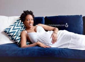 pregnancy mom smiling at camera while on couch laying