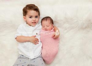 Livingston NJ newborn photography of siblings laying on white fur rug