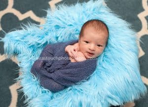 awake newborn boy photo laying on blue fur