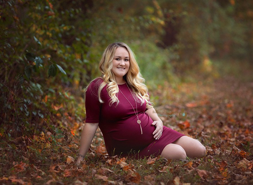 mom to be sitting for a photo holding belly