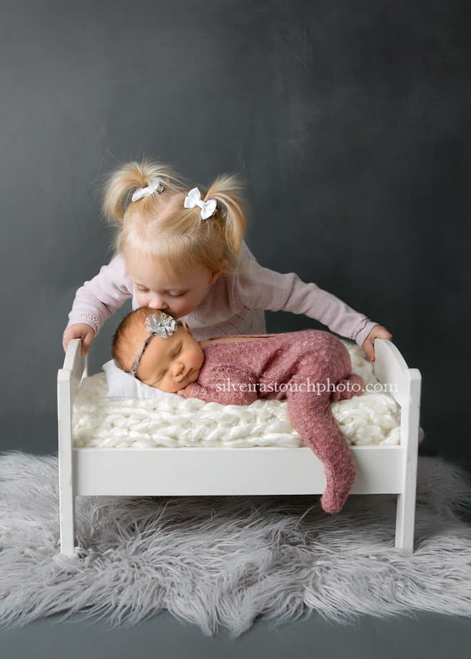 professional newborn photographer kissing her head gently