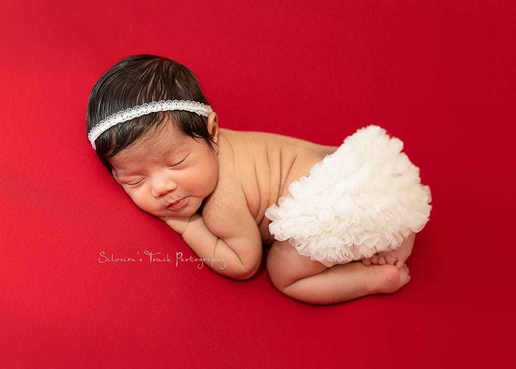 newborn baby photo sleeping on red blanket