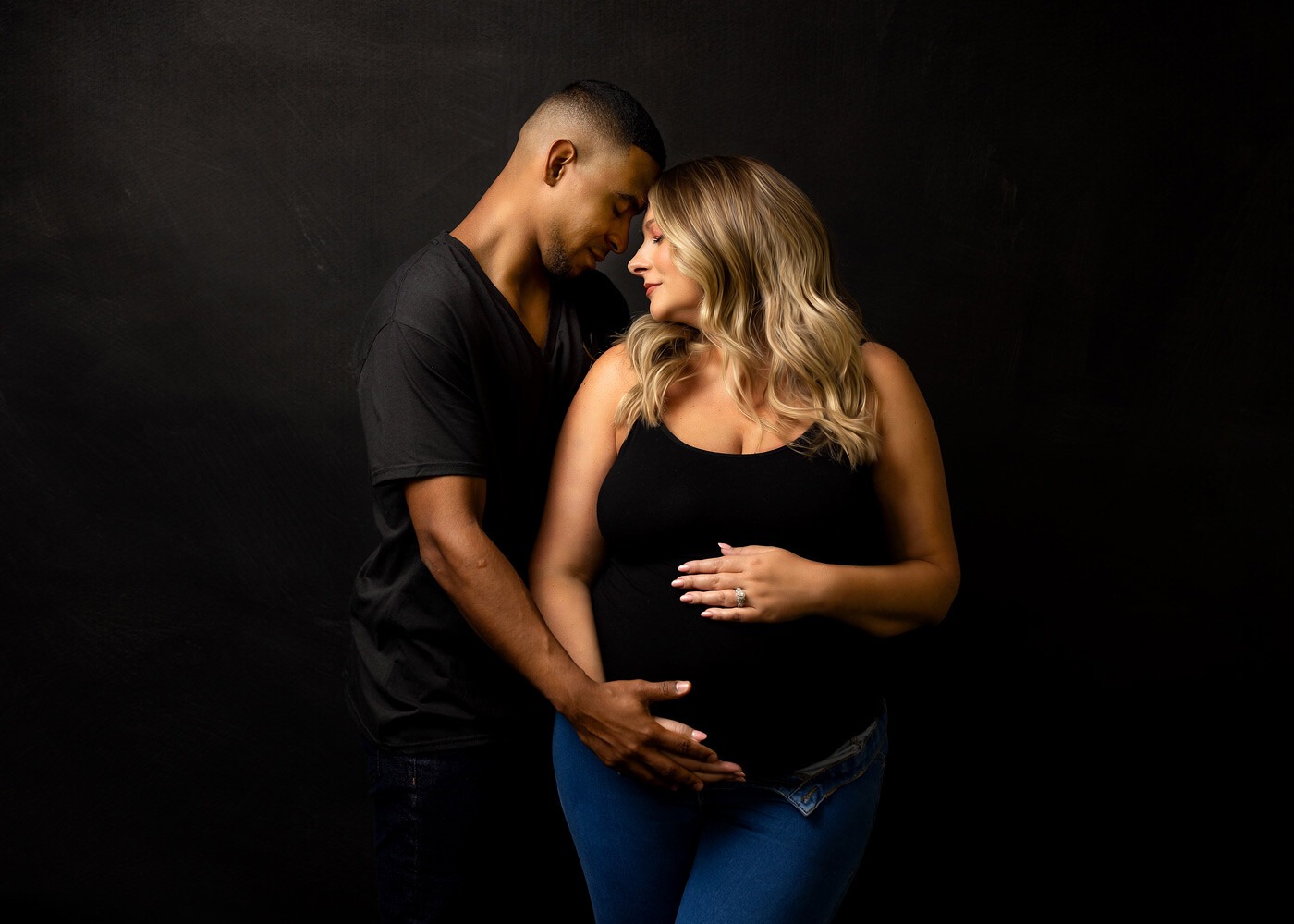 NJ Maternity photographer, couple posed holding moms baby bump dressed casual