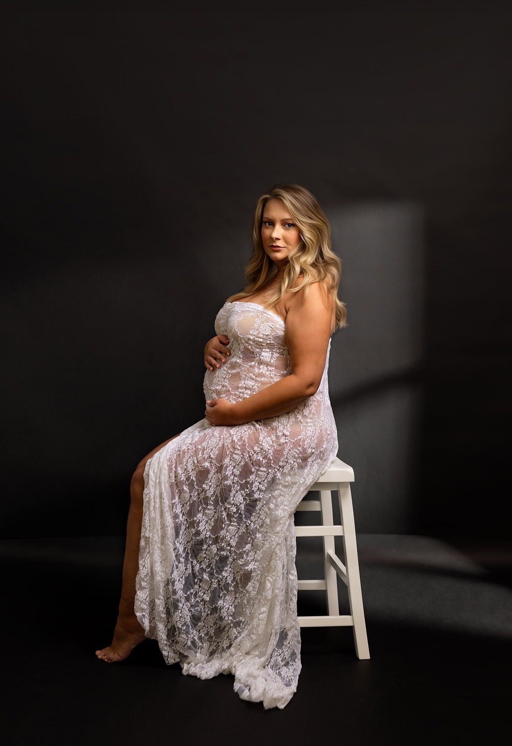 pregnancy shoot Dover NJ, mom wearing a white lace posed sitting on a white bench