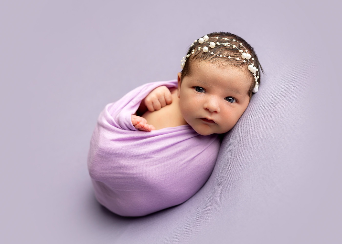 newborn baby girl photo shoot with eyes open on lavendar wrap 