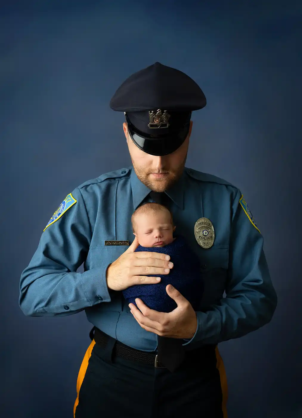 police officer photo holding his newborn baby photographed in Mount Olive NJ studio