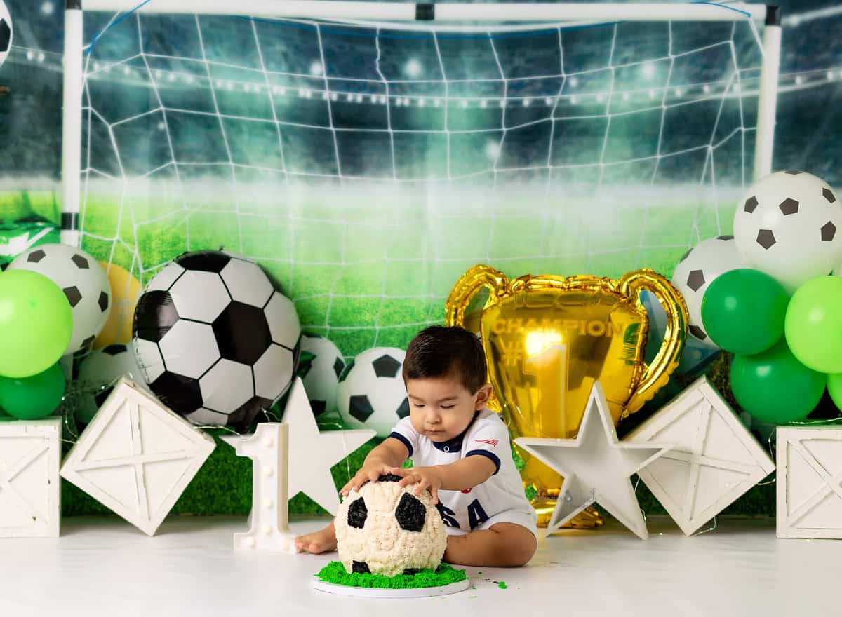 boy digging in to his Soccer cake during his first birthday portrait session