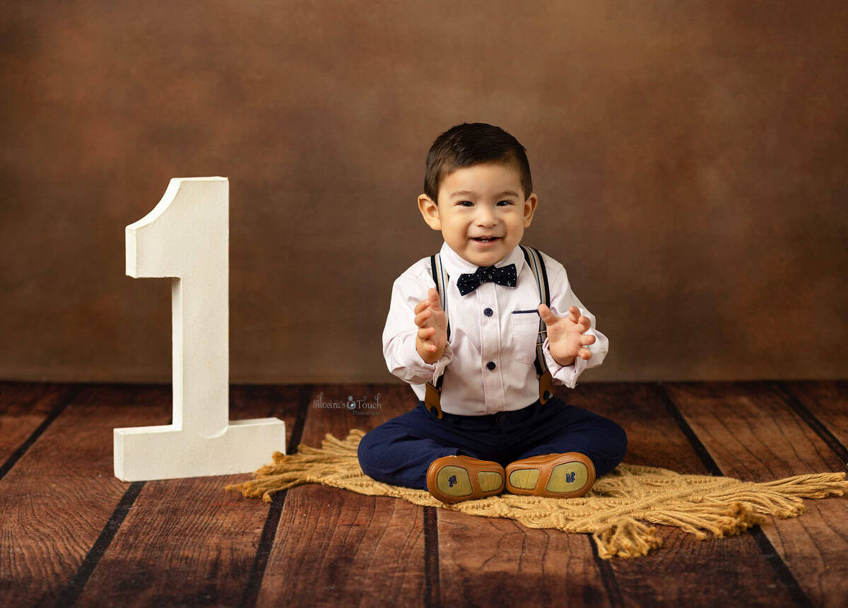 baby boy smiling sitting next to a number 1 sign during his birthday photo shoot in Randolph NJ